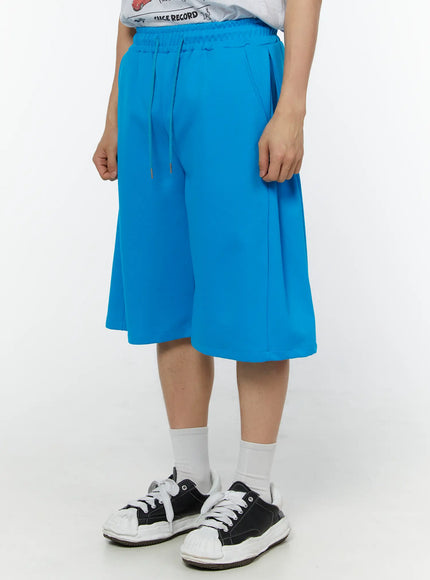 Men's Wide Leg Bermuda Sweat Shorts (Light blue) IU529 Light blue angled front view on model showing side pocket detail and relaxed wide-leg fit with drawstring elastic waistband