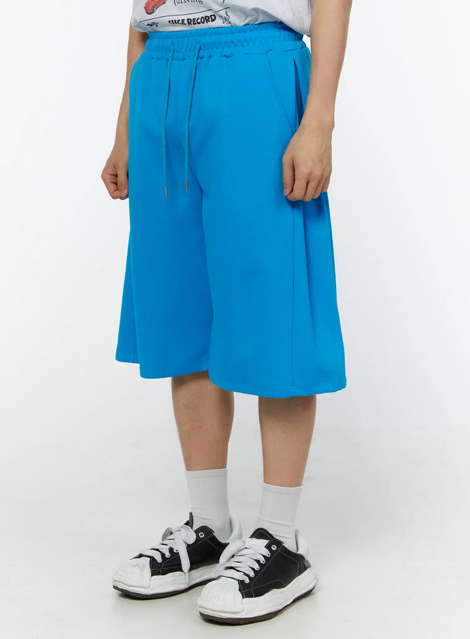 Men's Wide Leg Bermuda Sweat Shorts (Light blue) IU529 Light blue angled front view on model showing side pocket detail and relaxed wide-leg fit with drawstring elastic waistband