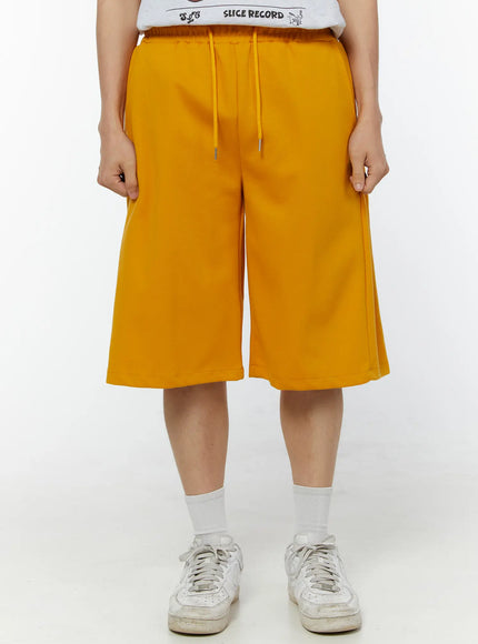 LEWKIN Men's Wide Leg Bermuda Sweat Shorts (Yellow) IU529 yellow front view on model wearing white graphic tee and sneakers, wide-leg silhouette with drawstring waist