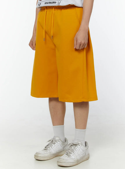 Men's Wide Leg Bermuda Sweat Shorts (Yellow) IU529 yellow angled front view on model showing wide-leg cut, elastic drawstring waistband and side seam detail