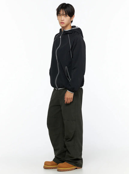 Men's Wide Leg Cargo Pants IL528 dark olive full-body side view on male model styled with black piping hooded windbreaker and tan boots