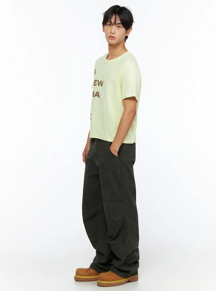 Men's Wide Leg Cargo Pants IL528 dark olive full-body side view on male model styled with yellow graphic cropped tee hand in pocket with tan boots