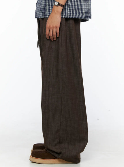Men's Wide Leg Cotton Pants IL528 Dark brown side shot on model showing single-leg profile with drawstring detail and wide straight leg hem pooling at shoe