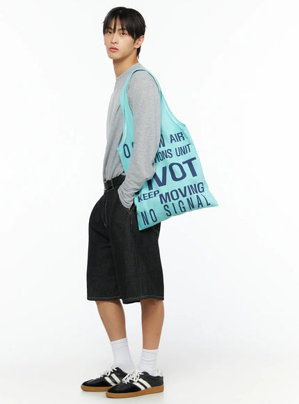 Men's Wide Leg Jorts IL528 Black side view on model carrying mint tote bag, showing wide-leg silhouette and knee length, styled with gray long-sleeve top