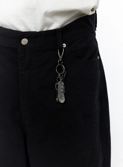 Men's Wide Leg Pants IU523 Black close-up detail of waistband showing metal carabiner clip with feather and ring keychain charm on denim