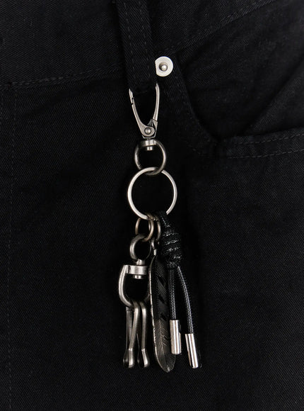 Men's Wide Leg Pants IU523 Black close-up detail of metal carabiner keychain with feather charm rope cord and silver rings clipped to waistband