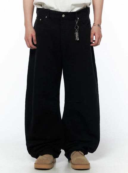 Men's Wide Leg Pants IU523 Black front view on model cropped at waist showing silver rivet detail and metal feather keychain charm