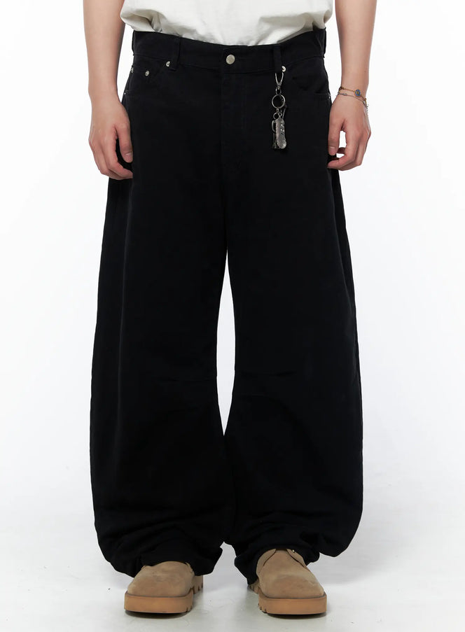 Men's Wide Leg Pants IU523 Black front view on model cropped at waist showing silver rivet detail and metal feather keychain charm