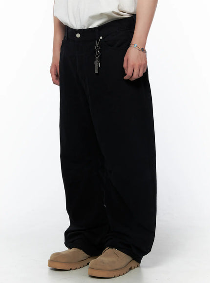 Men's Wide Leg Pants IU523 Black side view on model showing wide leg silhouette with metal keychain charm at waist and tan chunky shoes