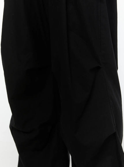 Men's Wide Leg Parachute Pants IL513 Black close-up detail shot showing thigh panel seam construction and lightweight fabric texture with draped folds