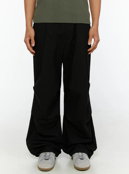 LEWKIN Men's Wide Leg Parachute Pants IL513 Black front crop shot on model wearing green henley tee and white sneakers, wide-leg silhouette with gathered hem