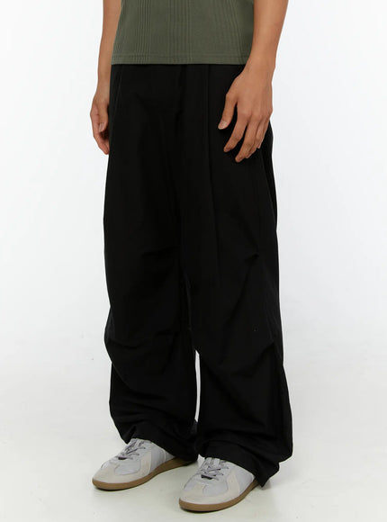 Men's Wide Leg Parachute Pants IL513 Black side-angle close-up on model showing voluminous wide leg drape and gathered ankle with white sneakers