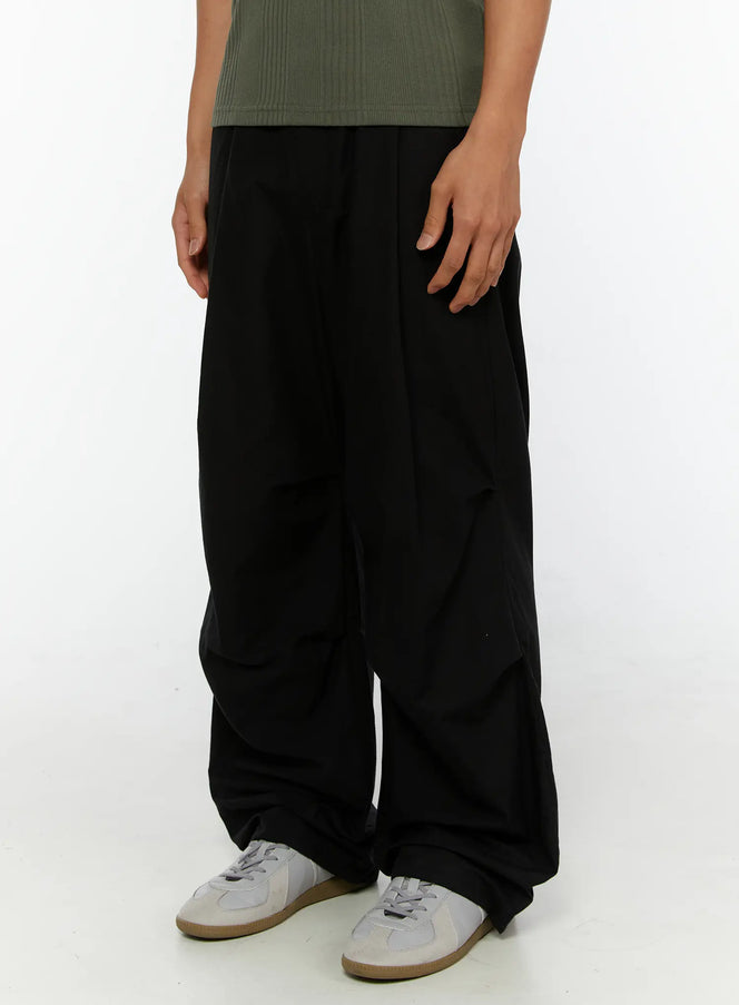 Men's Wide Leg Parachute Pants IL513 Black side-angle close-up on model showing voluminous wide leg drape and gathered ankle with white sneakers