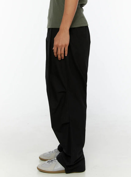 Men's Wide Leg Parachute Pants IL513 Black side shot on model showing straight silhouette from hip to gathered hem, paired with green ribbed tee and white sneakers
