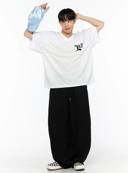 Men's Wide Leg Sweatpants (Black) IL514 black full-body front on male model holding light blue cap raised, white graphic tee, wide-leg balloon silhouette with drawstring waist