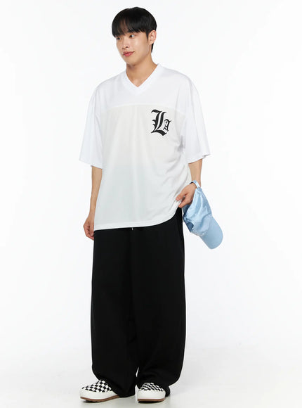Men's Wide Leg Sweatpants (Black) IL514 black full-body front on male model in white graphic tee looking to side, holding blue cap, ultra-wide leg and elastic waist visible