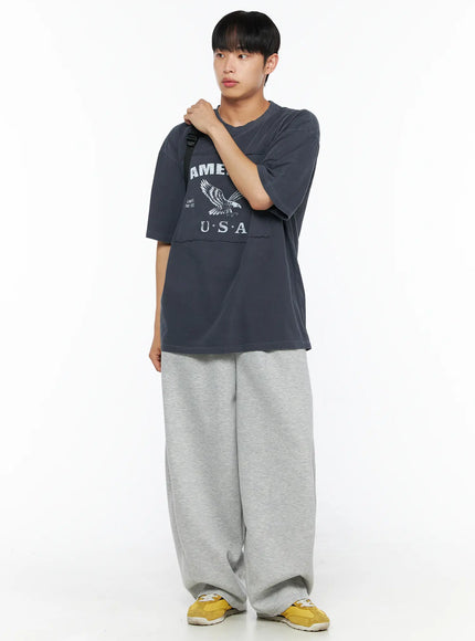Men's Wide Leg Sweatpants IL510 Gray full-body front shot on model with black crossbody bag showing tucked-out graphic tee and oversized balloon leg fit