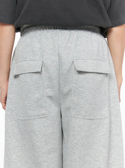 Men's Wide Leg Sweatpants IL510 Gray three-quarter front shot on model gripping bag strap styled with charcoal graphic tee and yellow sneakers