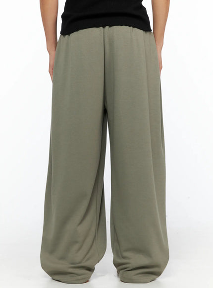 Men's Wide Leg Sweatpants IL528 Dark green front full-body shot on male model hands in pockets, grey ribbed tank, cream drawstring detail at waist