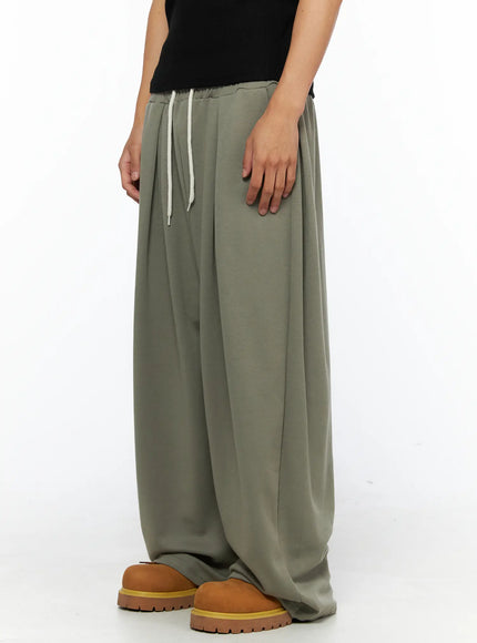 Men's Wide Leg Sweatpants IL528 Dark green side shot on male model styled with grey ribbed tank top and tan chunky shoes, angled pose