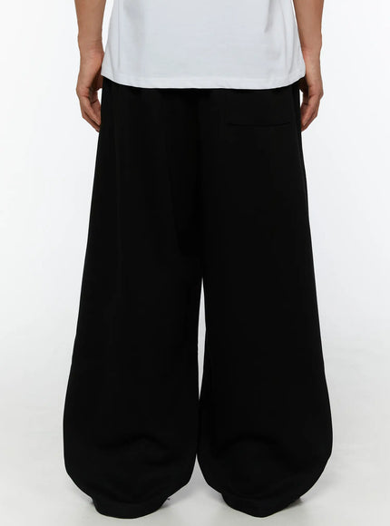 Men's Wide Sweatpants (Black) IL507 Black back shot on male model showing elastic waistband detail, wide balloon-leg back view and back pocket