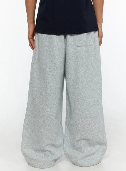 Men's Wide Sweatpants (Gray) IL507 Gray back view on male model showing wide balloon-leg silhouette elastic waistband and back welt pocket in heathered gray fleece