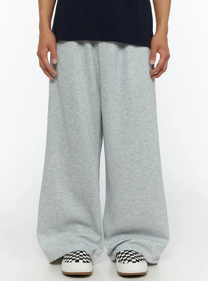 LEWKIN Men's Wide Sweatpants (Gray) IL507 Gray M/L front close-up on male model showing wide-leg heathered fleece fabric and elastic waistband styled with navy tee and checkered sneakers