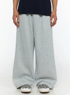 LEWKIN Men's Wide Sweatpants (Gray) IL507 Gray M/L front close-up on male model showing wide-leg heathered fleece fabric and elastic waistband styled with navy tee and checkered sneakers