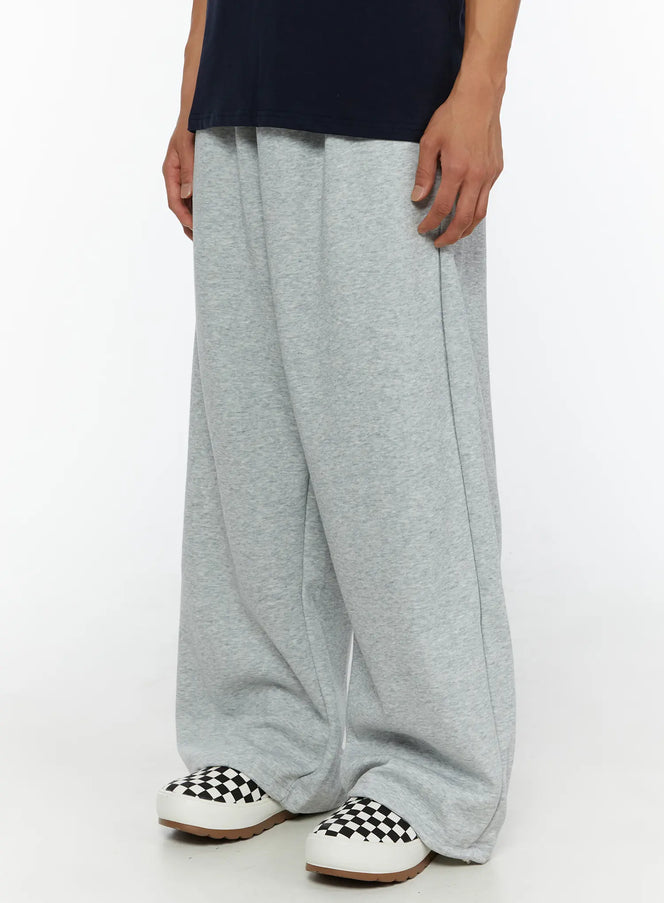 Men's Wide Sweatpants (Gray) IL507 Gray angled close-up on male model highlighting side seam pintuck detail and wide-leg silhouette in heathered gray fleece with checkered slip-ons