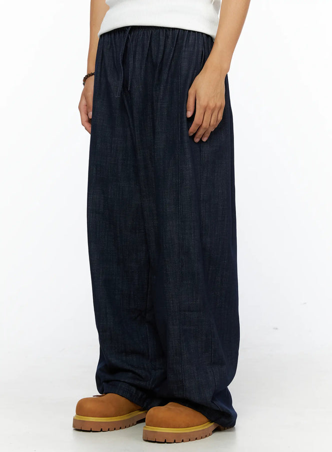 Men's Zack Wide Leg Jeans IL528 Dark blue side view on model showing elastic waistband detail, drawstring tie, and wide-leg denim silhouette with chunky boots