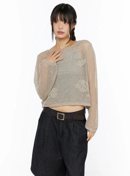 Mesh Knit Sweater CU530 Beige side view on model styled with dark denim pants brown belt hand resting on chest sheer crochet floral mesh knit