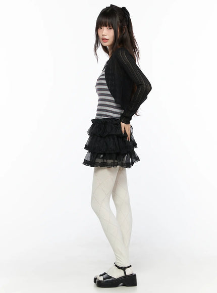 Mesh Tiered Mini Skirt CL522 Black side full-body shot on model showing tiered ruffle silhouette profile paired with sheer black cardigan and white tights