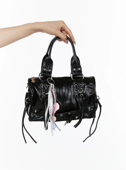 LEWKIN Metallic Detail Shoulder Bag CL508 Black front view held aloft by model's hand showing crinkled faux leather with silver hardware and pink charm tassel