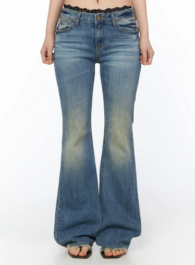 LEWKIN Moira Washed Low-Rise Bootcut Jeans IL502 Blue front view on model, cropped shot from waist down, flared hem with frayed edge, washed denim texture, lace waistband peeking above