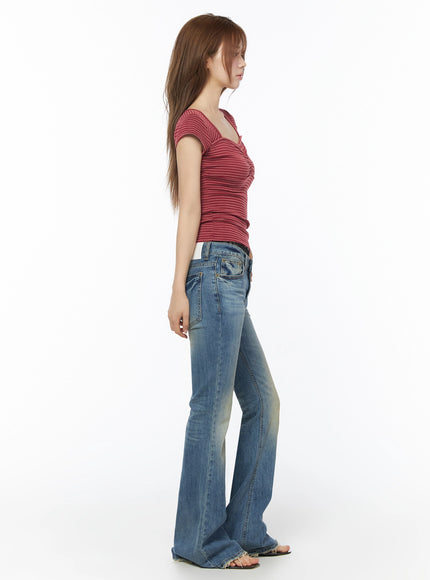 Moira Washed Low-Rise Bootcut Jeans IL502 Blue full-body side view on model wearing red striped top, showing slim thigh-to-wide flare silhouette and frayed raw hem, white background