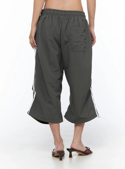 Nylon Track Bermuda Pants CU523 Dark gray back shot on model showing elastic waistband back patch pocket white side stripes and wide cropped leg