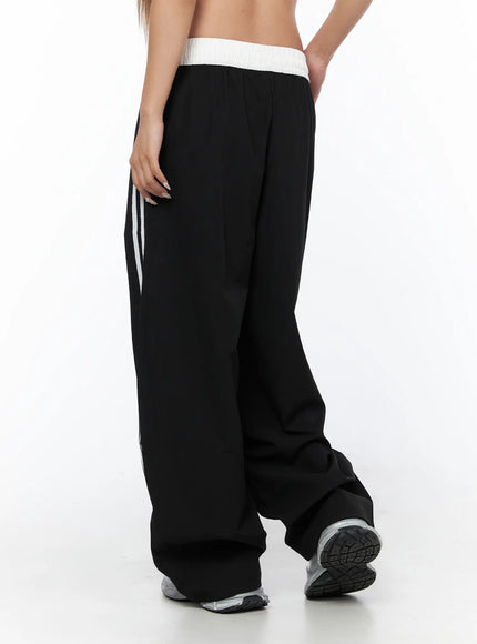 Nylon Track Pants CU523 Black rear three-quarter close-up on model highlighting white contrast waistband texture and back panel drape