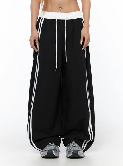 Nylon Track Pants CU523 Black S/M front close-up on model showing white contrast waistband, drawstring, and double white side stripes