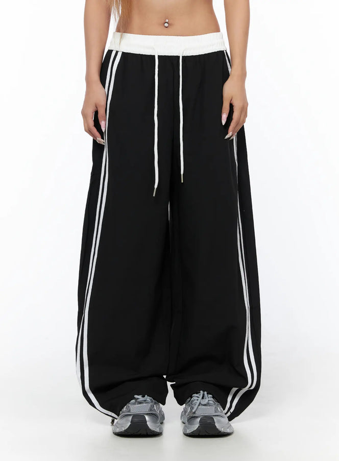 Nylon Track Pants CU523 Black S/M front close-up on model showing white contrast waistband, drawstring, and double white side stripes