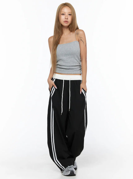 Nylon Track Pants CU523 Black full-length front shot on model wearing gray crop cami top and silver sneakers, hands in pockets