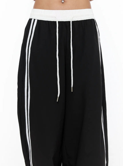 Nylon Track Pants CU523 Black close-up detail of white contrast waistband, white rope drawstring with metal aglet, and side stripe at hip