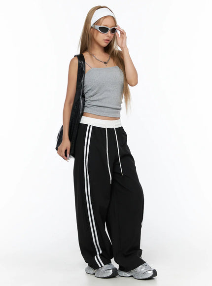 Nylon Track Pants CU523 Black styled shot on model with sunglasses, white headband, black bag, and gray cami in sporty street look