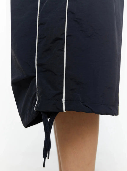 Nylon Wide-Leg Shorts IL524 Dark blue close-up detail of hem showing contrast white piping, crinkled nylon texture, side slit, and black drawstring cord