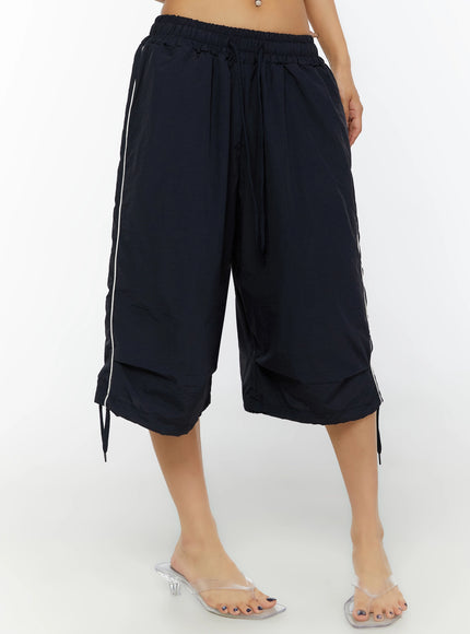 Nylon Wide-Leg Shorts IL524 Dark blue front three-quarter shot on model showing drawstring waist, side white piping, and double-layer hem with ties