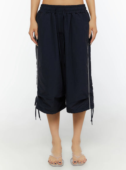 Nylon Wide-Leg Shorts IL524 Dark blue front shot on model showing wide cropped silhouette, white side piping, layered hem, and ankle tie drawstrings