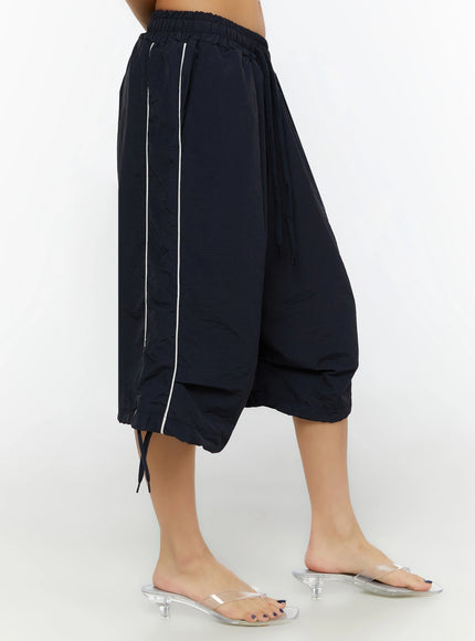 Nylon Wide-Leg Shorts IL524 Dark blue side three-quarter shot on model showing white piping stripe, voluminous wide leg, and ankle drawstring hem
