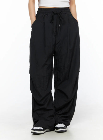 Nylon Wide Pants CL514 Black front view on model with hands in pockets, elastic drawstring waistband and wide-leg crinkled nylon silhouette