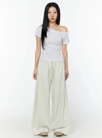 Off-Shoulder Buttoned Slit Tee IU524 White front shot model full body standing arms down styled with cream wide-leg pants