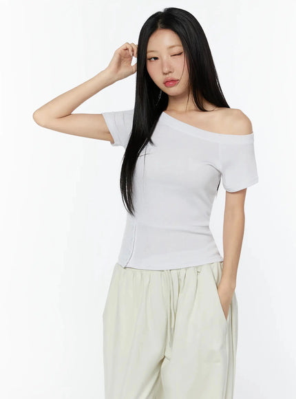 Off-Shoulder Buttoned Slit Tee IU524 White front shot model half-body hand raised to hair showing asymmetric shoulder and ribbed waist detail