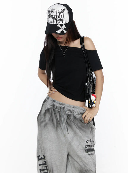 LEWKIN Off-Shoulder Casual Tee CL527 Black S/M front shot on model wearing cap and grey sweatpants, asymmetric off-shoulder neckline, fitted ribbed crop silhouette